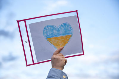 Low angle view of woman holding basketball hoop against sky