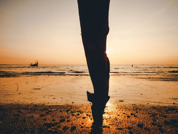 Low section of silhouette person standing on beach