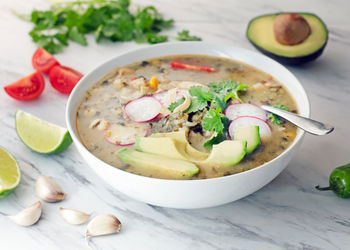 Delicious healthy bowl of vegetable noodle soup on marble counter.