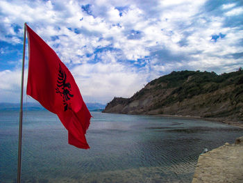 Red flag by sea against sky