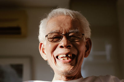 Close-up portrait of smiling senior man at home