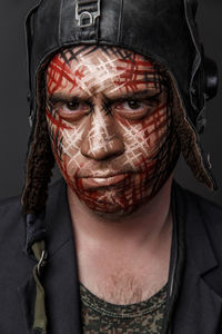 Close-up of man with face paint against black background