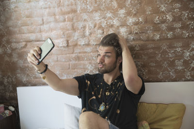 Young man taking a selfie on his bed