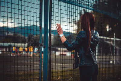 Rear view of woman standing by fence