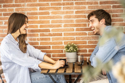 Side view of couple sitting on table