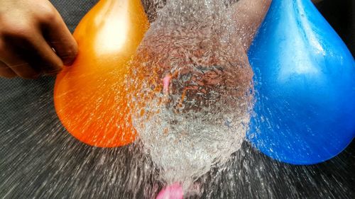 Midsection of person bursting balloons with water