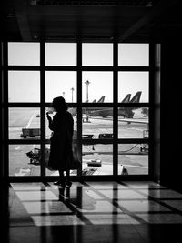 Rear view of silhouette woman standing by window