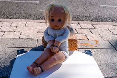 High angle view of cute girl sitting on footpath