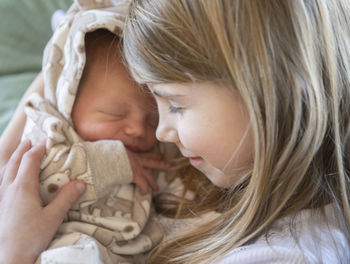 Close-up of cute girl holding sibling while sitting at home