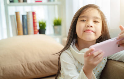 Portrait of girl holding smart phone at home