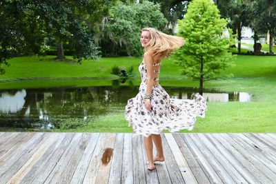 Teenage girl spinning while standing on boardwalk 