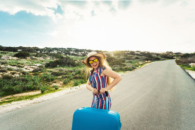 Young woman standing on road against sky