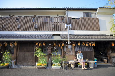 Full length of woman sitting outside building