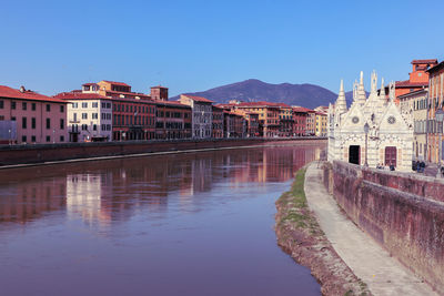 Buildings at waterfront against blue sky