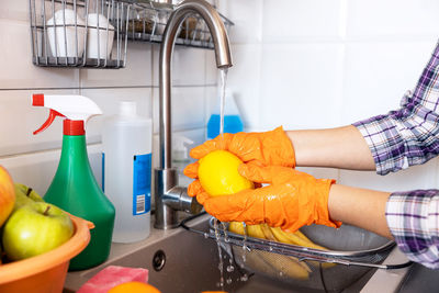 Washing fresh fruits in the kitchen under cold running tap water