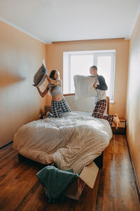 Young woman sitting on bed at home