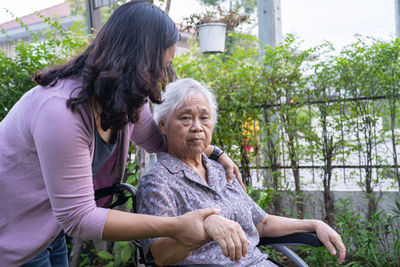 Doctor caregiver help and care asian senior woman patient sitting on wheelchair in park