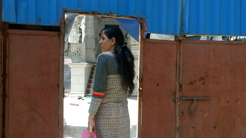 Rear view of woman entering from metallic gate