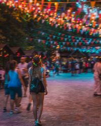 Rear view of women walking on illuminated street