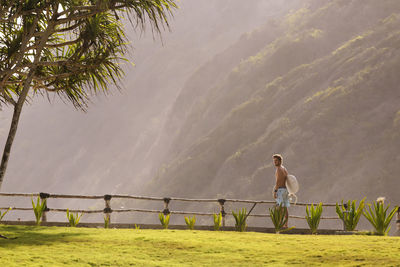 Young man walking and carrying surfboard