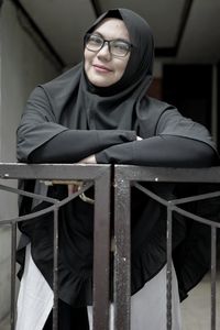 Portrait of smiling woman in hijab standing at railing