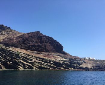 Scenic view of sea and mountains against clear blue sky