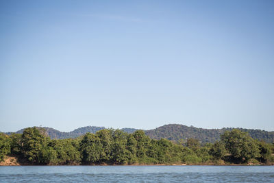 Scenic view of lake and mountains against clear blue sky