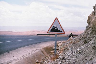 View of road sign on landscape against sky