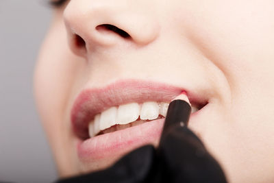 Cropped hand of beautician applying lipstick on woman lips at spa