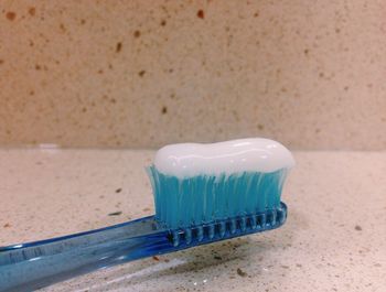 Close-up of toothpaste on blue plastic toothbrush in bathroom