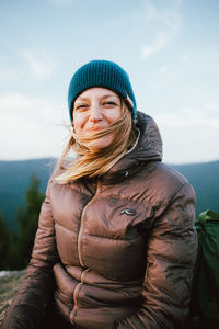 Portrait of woman sitting on rock against mountains