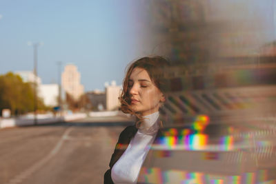 Young woman with eyes closed standing on road in city