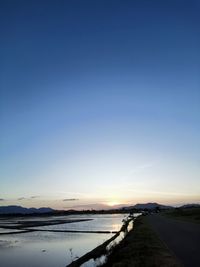 Scenic view of beach against clear sky at sunset