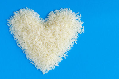 Rice in heart shape on blue background