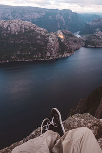 Person cross legged at edge of cliff with a fjords view in norway