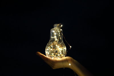 Close-up of illuminated light bulb over black background