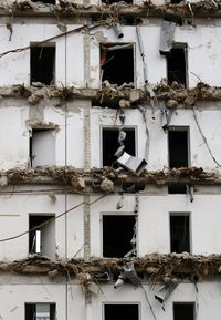 Tall building being demolished exposing cables and metal beams