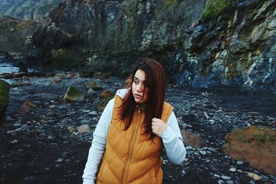 Beautiful young woman standing against waterfall