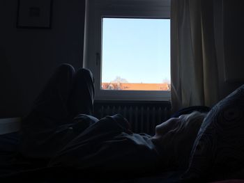 Woman sleeping on bed at home against clear sky