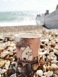 Close-up of coffee cup on beach