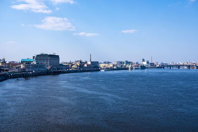 Sea by illuminated city against sky at dusk