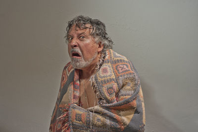 Portrait of young man looking away against wall