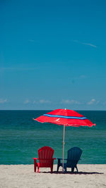 Deck chairs on beach against blue sky