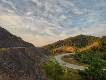 Scenic view of road by mountains against sky