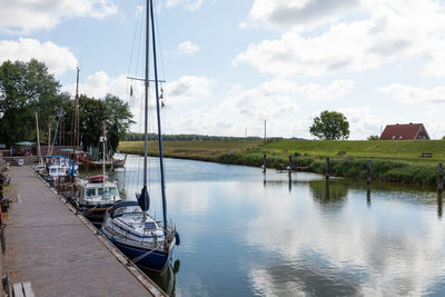 Sailboats moored in river against sky