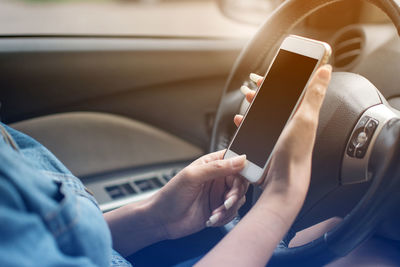 Close-up of hand holding smart phone in car