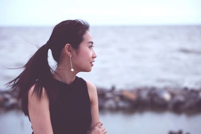 Thoughtful young woman against sea