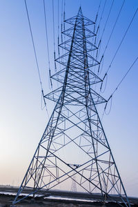 Low angle view of electricity pylon against clear sky