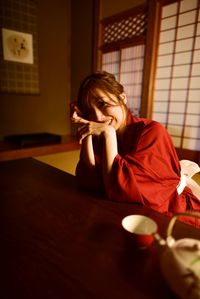 Young woman sitting on table at home