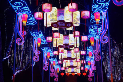 Close-up of illuminated lighting equipment hanging against black background